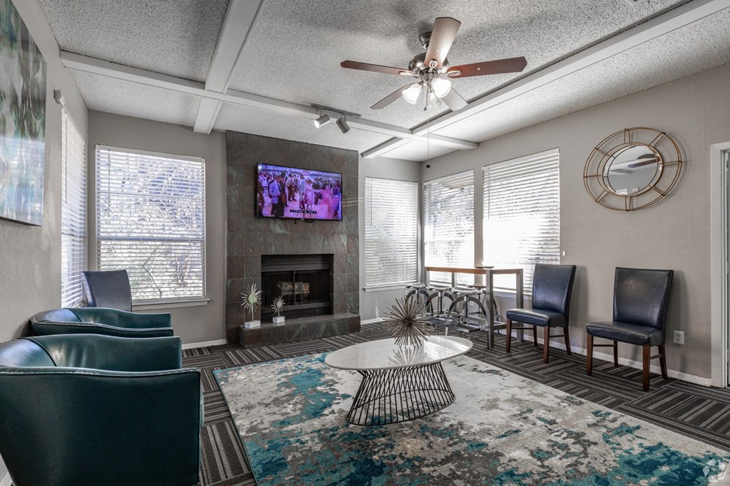 A leasing office with a fireplace, chairs, and a television at Preston Oaks Apartments in Dallas, TX.
