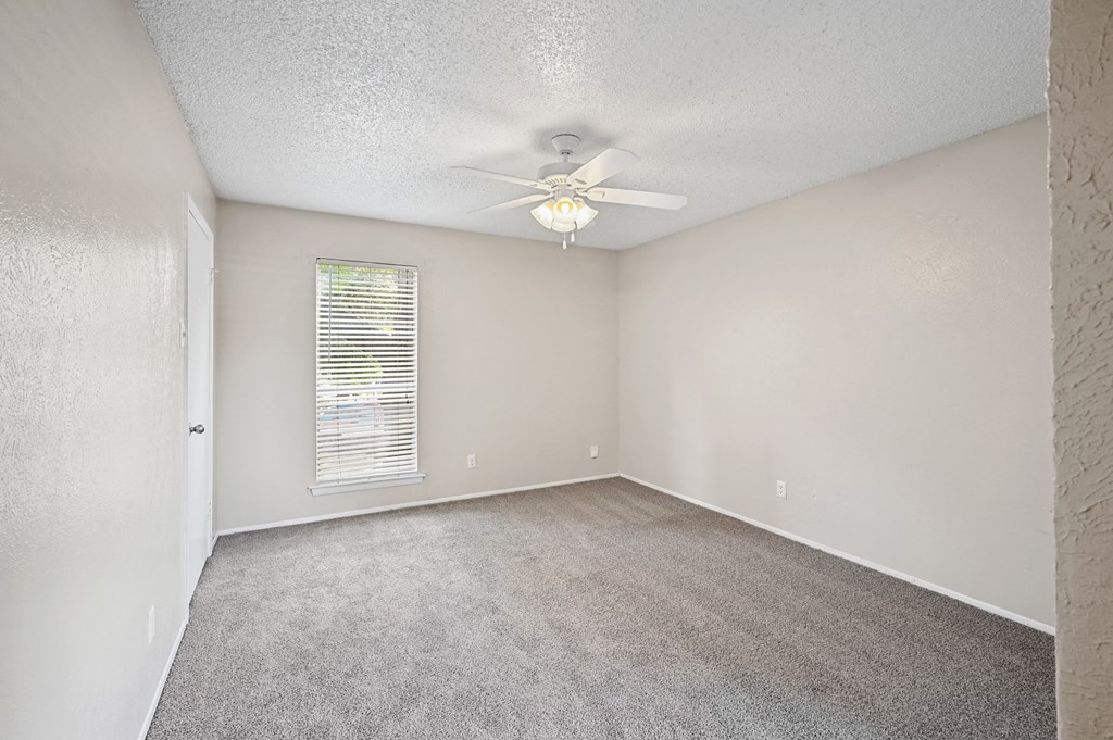 an empty bedroom with a ceiling fan