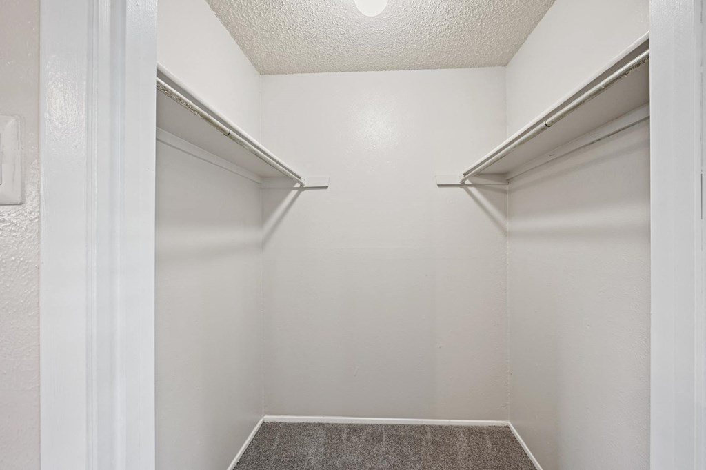 a walk in closet in a bedroom with white walls and a white ceiling