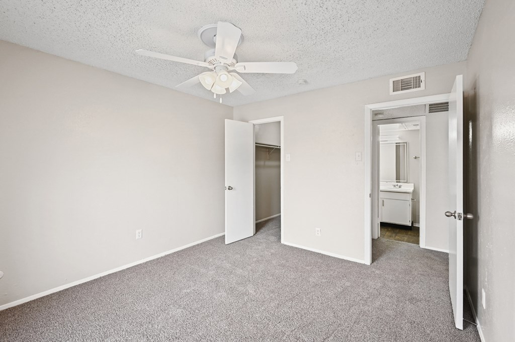 an empty bedroom with a ceiling fan