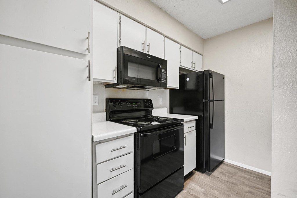 a kitchen with white cabinets and black appliances