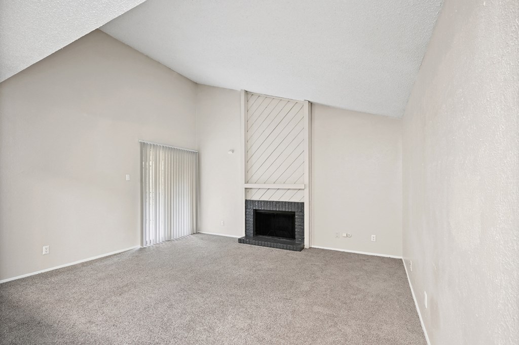 an empty living room with a fireplace and a sliding glass door