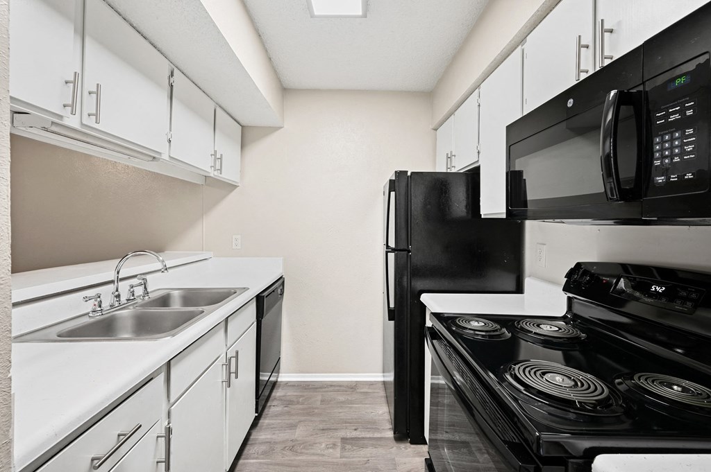 a kitchen with white cabinets and black appliances