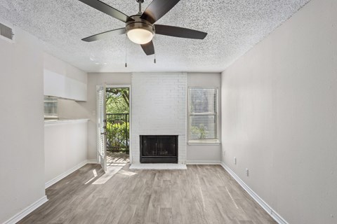 A white living room with a fireplace and a ceiling fan at The Park on Preston in Dallas, TX