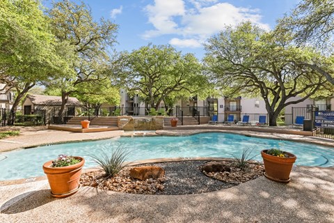 A pool surrounded by trees and potted plants at The Park on Preston in Dallas, TX