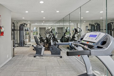 A gym with treadmills, elliptical machines and strength training equipment at The Park on Preston in Dallas, TX