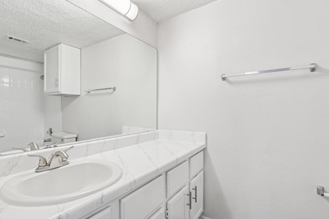 A white bathroom with a sink and a mirror at The Park on Preston in Dallas, TX