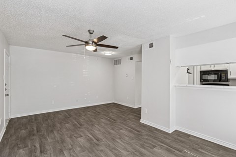 A white living room with a ceiling fan and wooden flooring at The Park on Preston in Dallas, TX