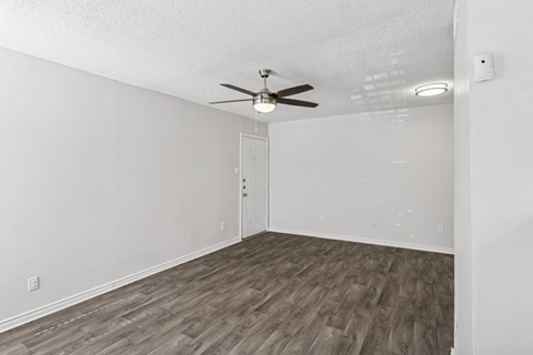A white living room with a ceiling fan and wooden flooring at The Park on Preston in Dallas, TX