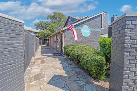 A stone pathway leads to a building with a sign for at "The Pearl" apartments in Shreveport LA