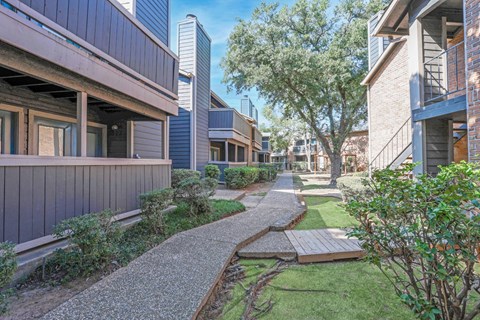 Walkways in between apartments with lush landscaping at The Pearl apartments in Shreveport, LA