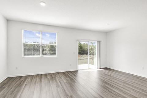 a spacious living room with white walls and hardwood floors