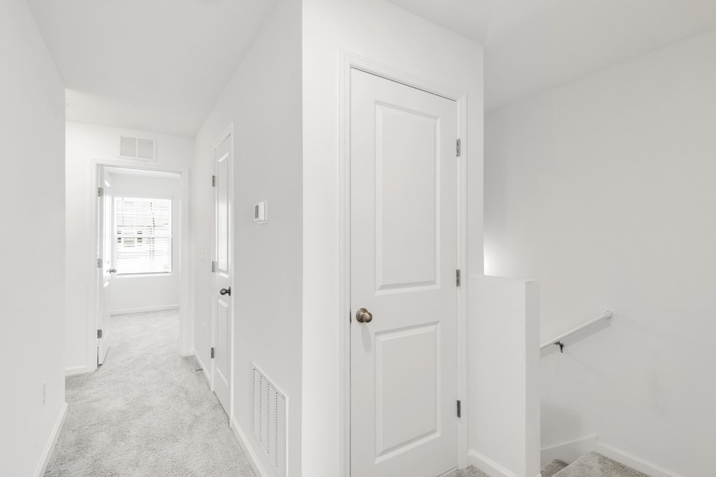 a hallway in a home with white walls and carpet