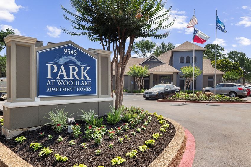 a parking lot with a sign that says park at woodlawn apartments - Photo Gallery 1