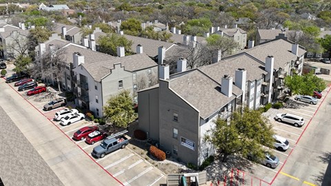 An aerial view of an apartment complex with parking and a dumpster at The Park on Preston Apartments in Dallas, TX
