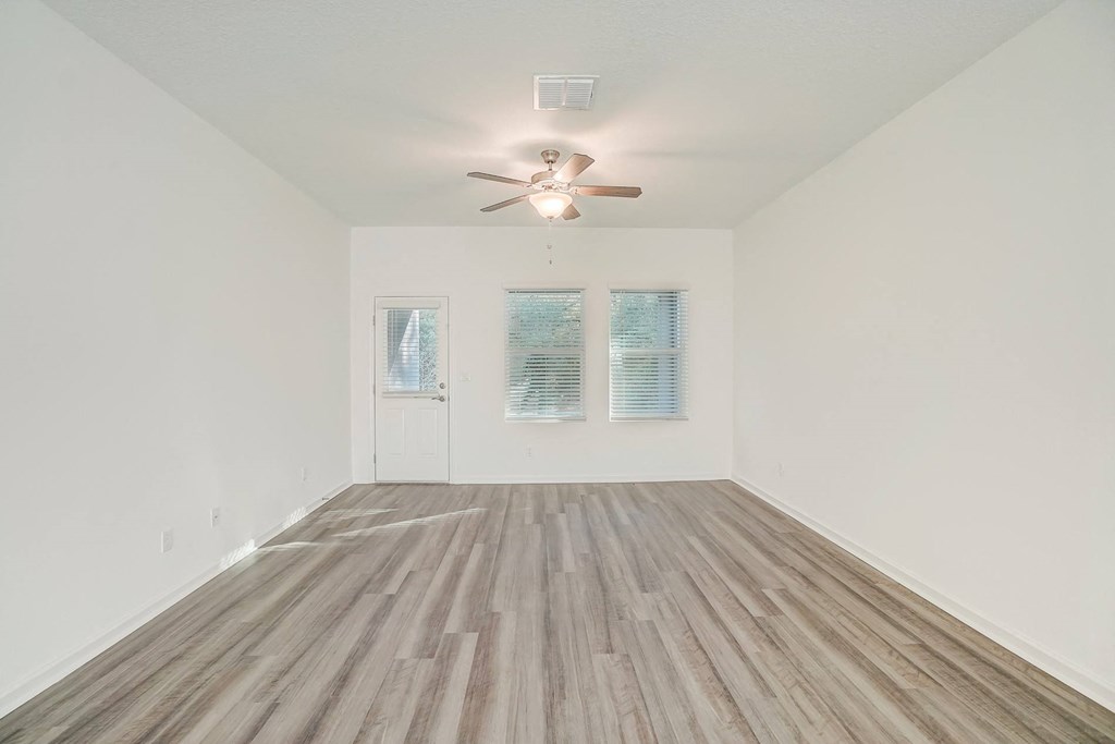 an empty living room with a ceiling fan and wood floors