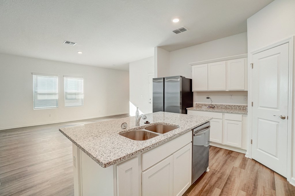 an empty kitchen with white cabinets and a counter top