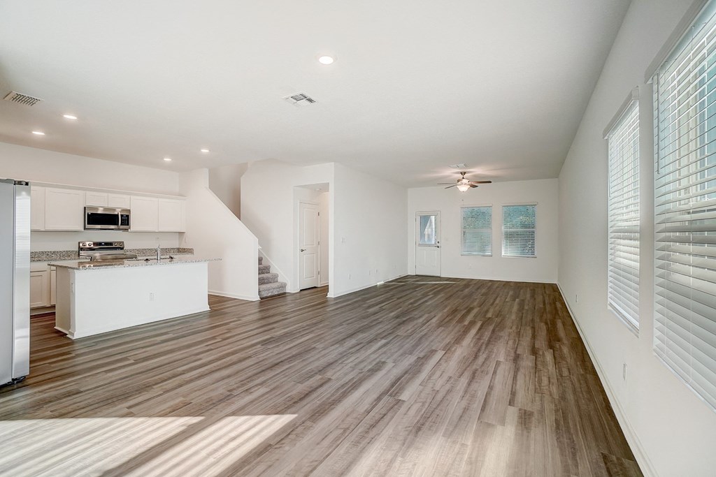 an empty living room and kitchen with wood flooring