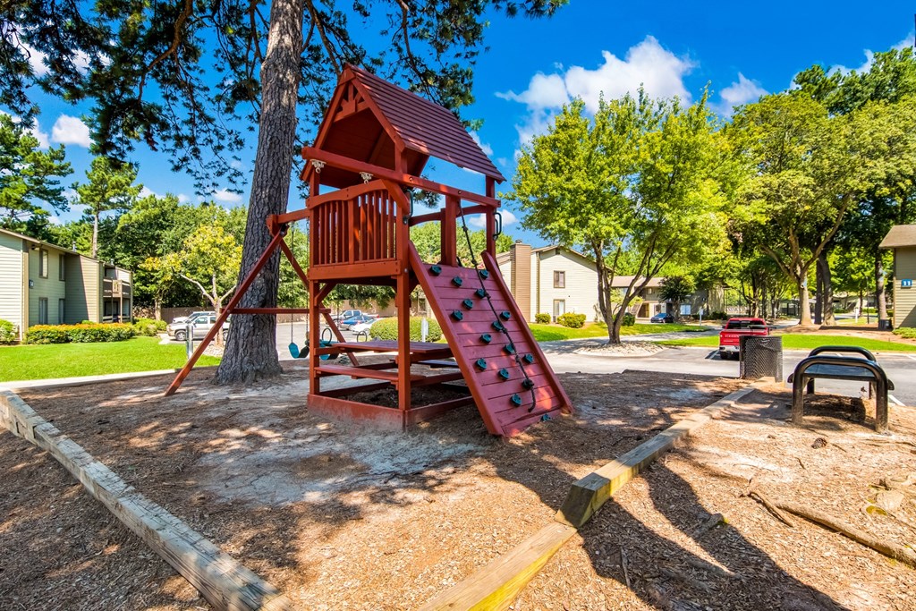 a red swing set in a park next to a tree