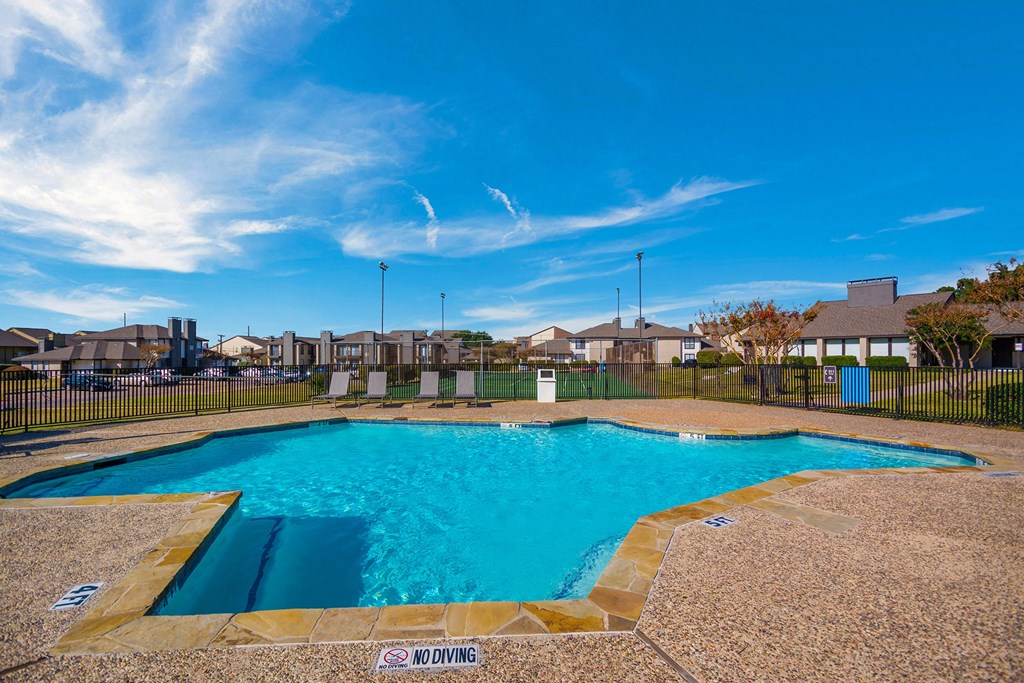 a swimming pool with a blue sky and houses in the background