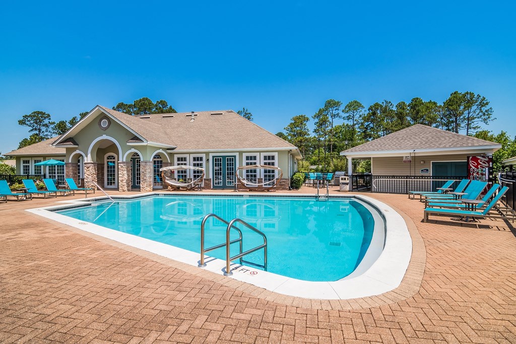 a swimming pool with chairs around it in front of a house