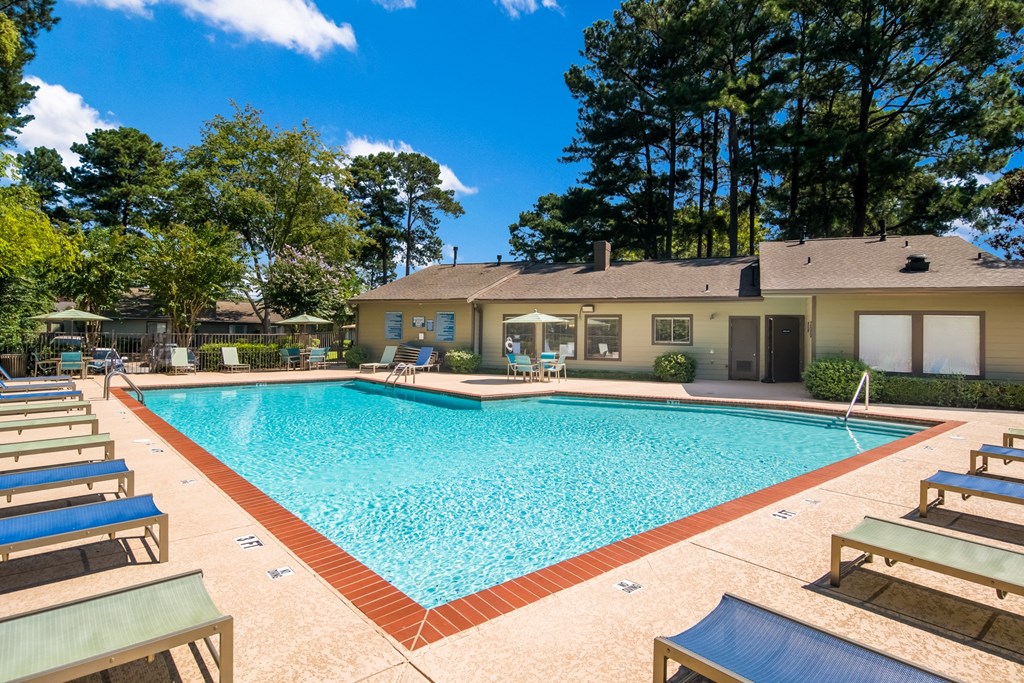 a swimming pool with chairs and a house in the background