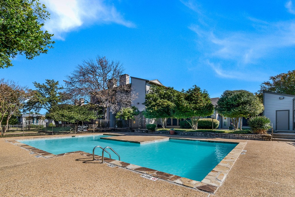a swimming pool with trees and a building in the background