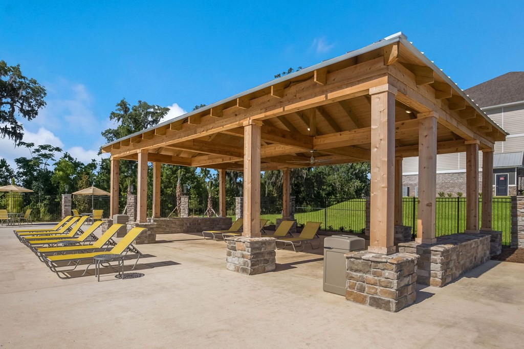 a pavilion with a fire pit and lounge chairs