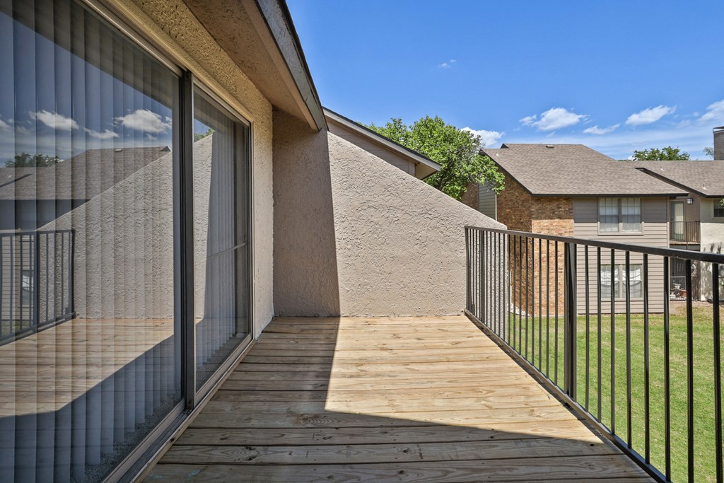 a balcony with a wooden deck and a glass sliding door