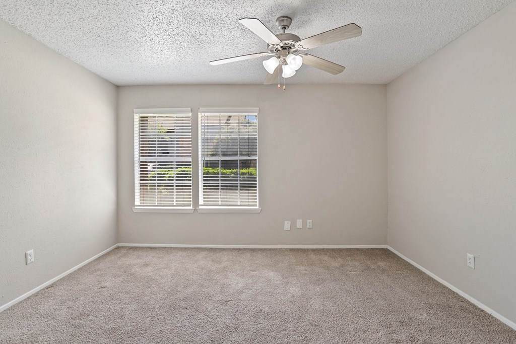 a bedroom with a ceiling fan and two windows