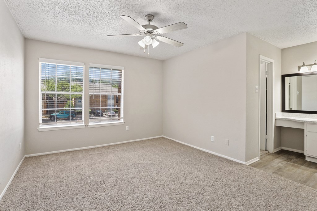 a bedroom with a large window and a ceiling fan