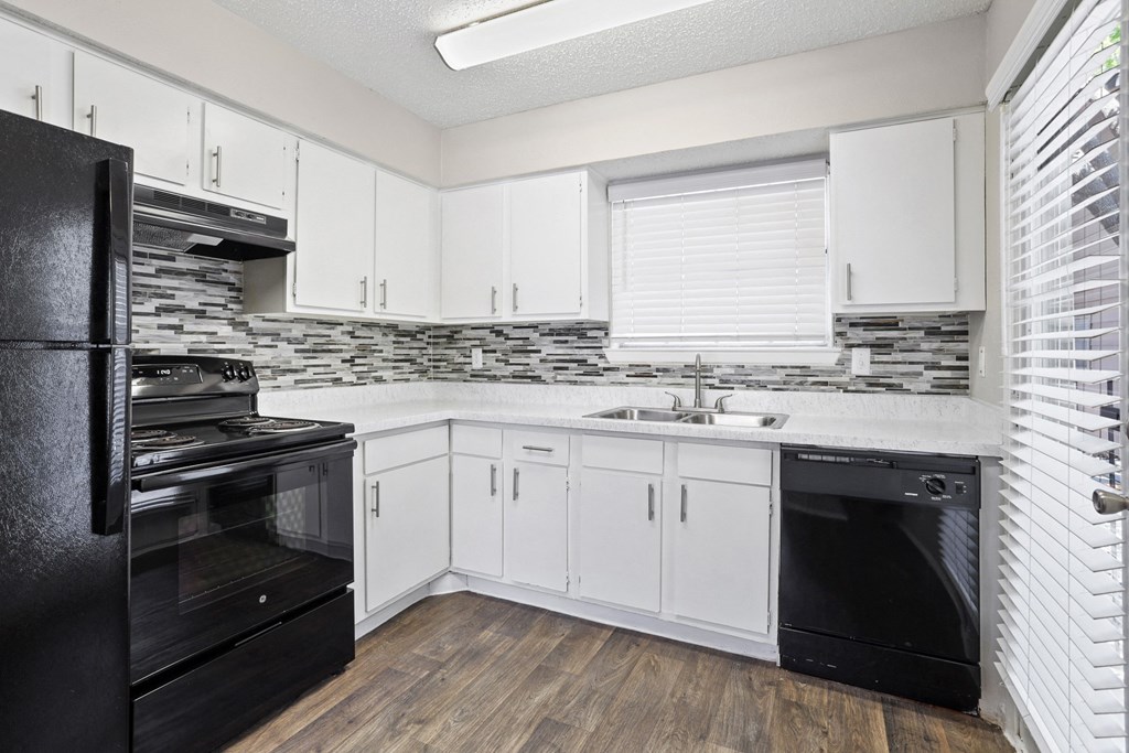 a kitchen with white cabinets and black appliances