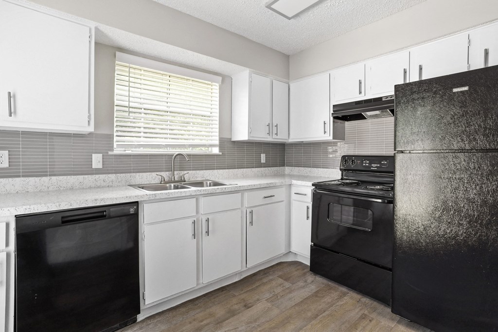 a kitchen with white cabinets and black appliances