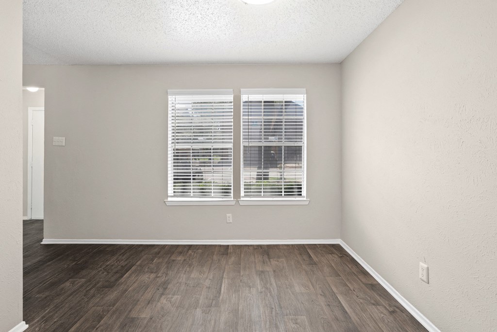 a bedroom with a large window and hardwood floors