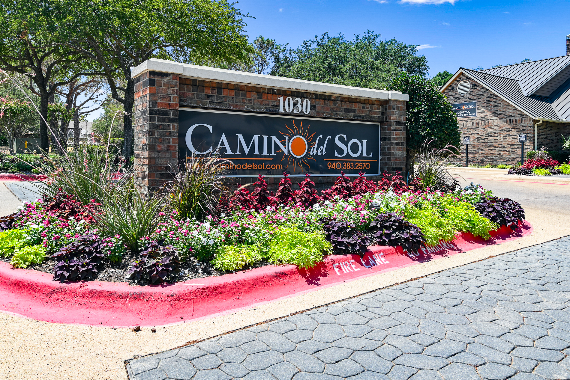 a sign for the camino real estate sold sign in front of a flower garden