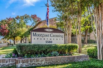 a sign for montgomery crossing apartments with an american flag and trees in the background