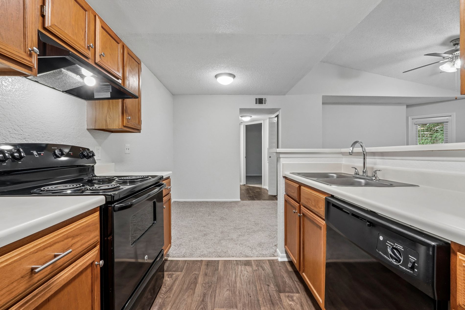A kitchen with a black stove top oven and wooden cabinets.