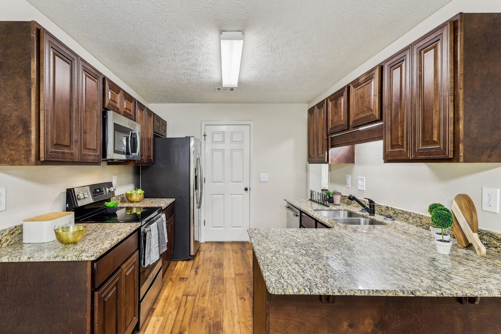 a kitchen with wooden cabinets and granite counter tops at Grand Reserve Columbus in Columbus, GA