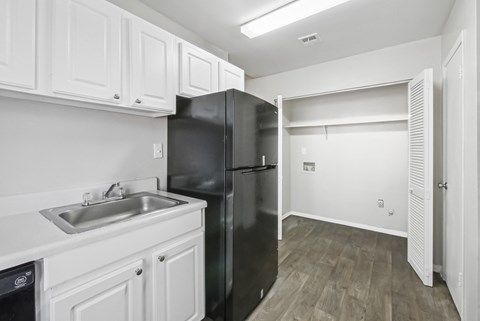 Kitchen with white cabinets and washer and dryer connections in C2b floor plan at Riverwood Crossing apartments in Roswell, GA.