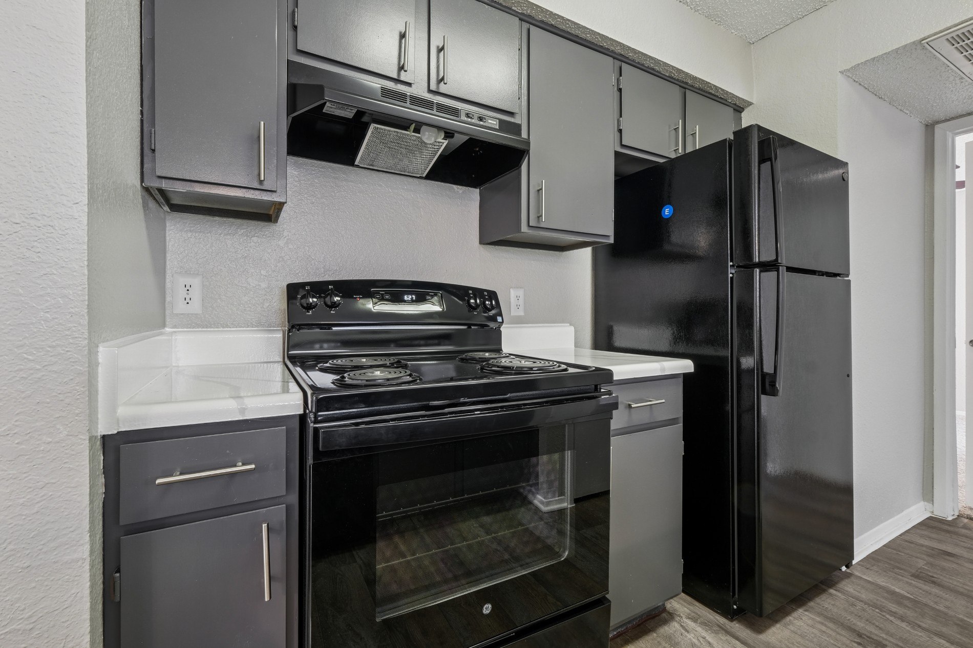 A black stove and refrigerator in a kitchen.