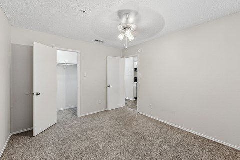 A spacious room with carpeted floor and white walls, featuring a ceiling light and four doors.