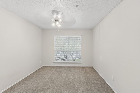 A room with a carpeted floor and a window with blinds.