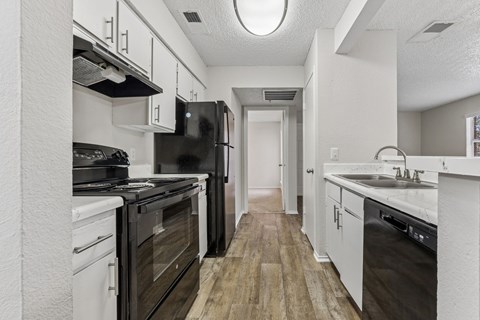 A kitchen with black appliances and white cabinets.