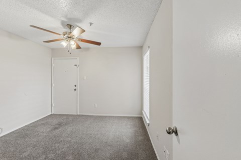 A room with a ceiling fan and carpeted floor.