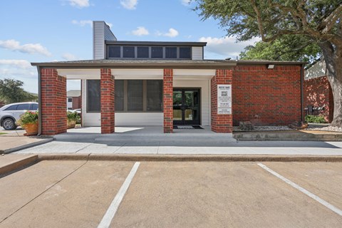 A red brick building with a white entrance and a sign on the right side.