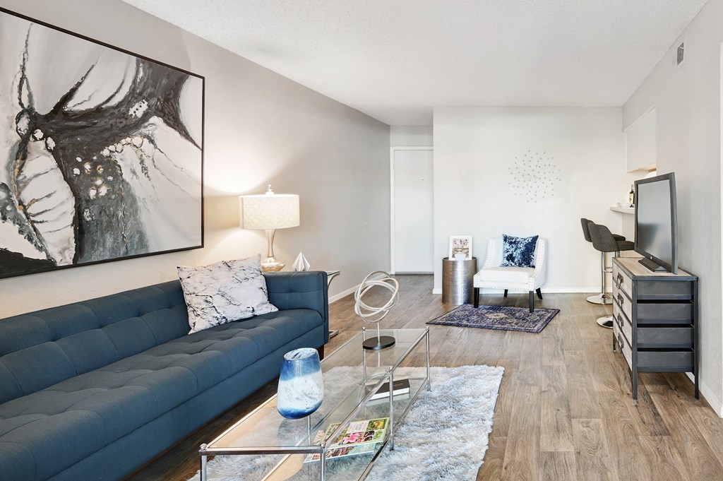 a living room with a blue couch and a glass coffee table