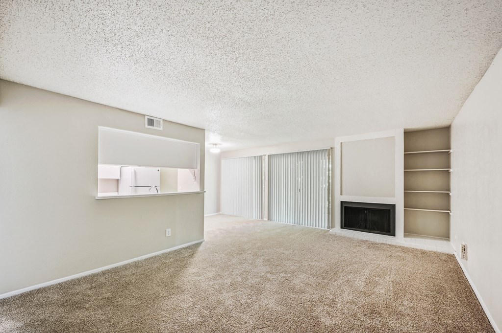 a spacious living room with carpeted flooring and a fireplace