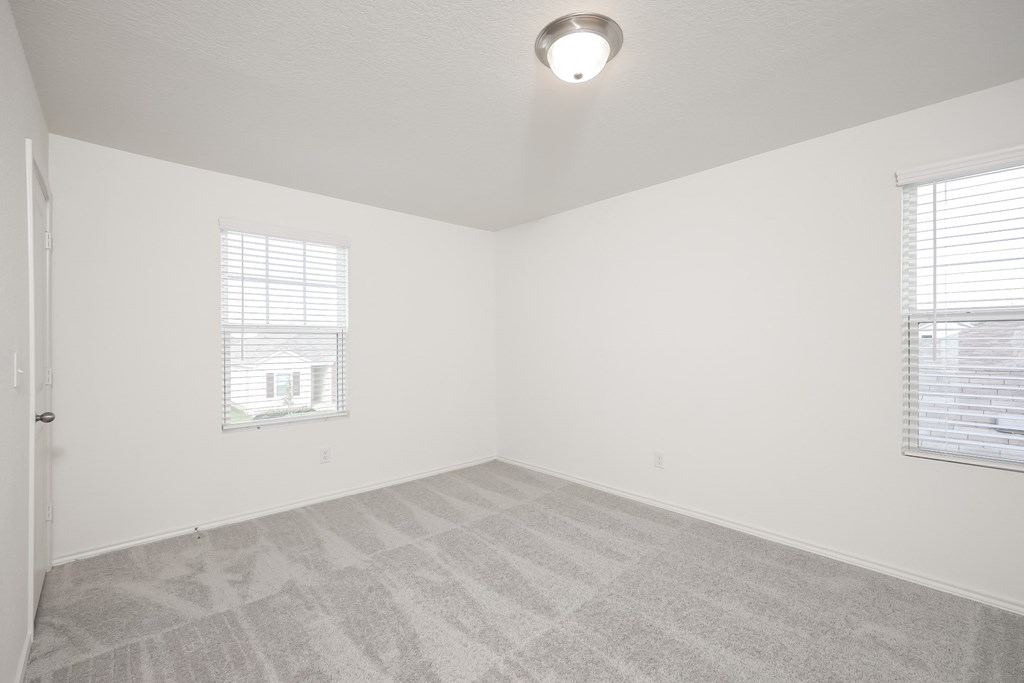 a bedroom with two windows and a carpeted floor at Beacon at Meridian, Texas