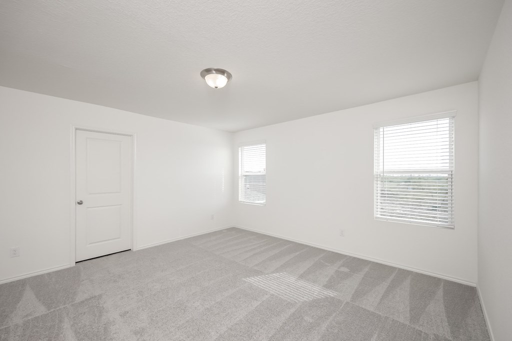 an empty bedroom with a door and two windows at Beacon at Meridian, Texas