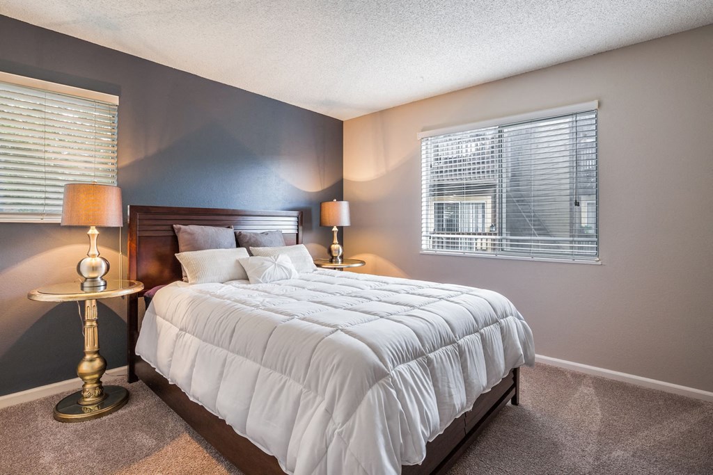 a bedroom with a bed and two lamps and a window